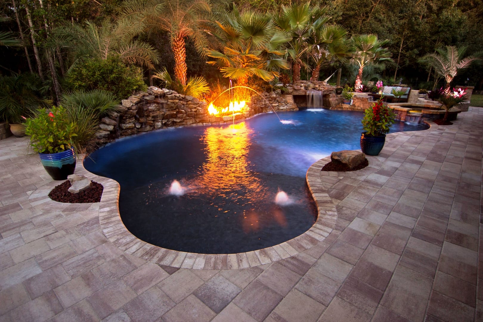 A pool with fire pit and brick patio